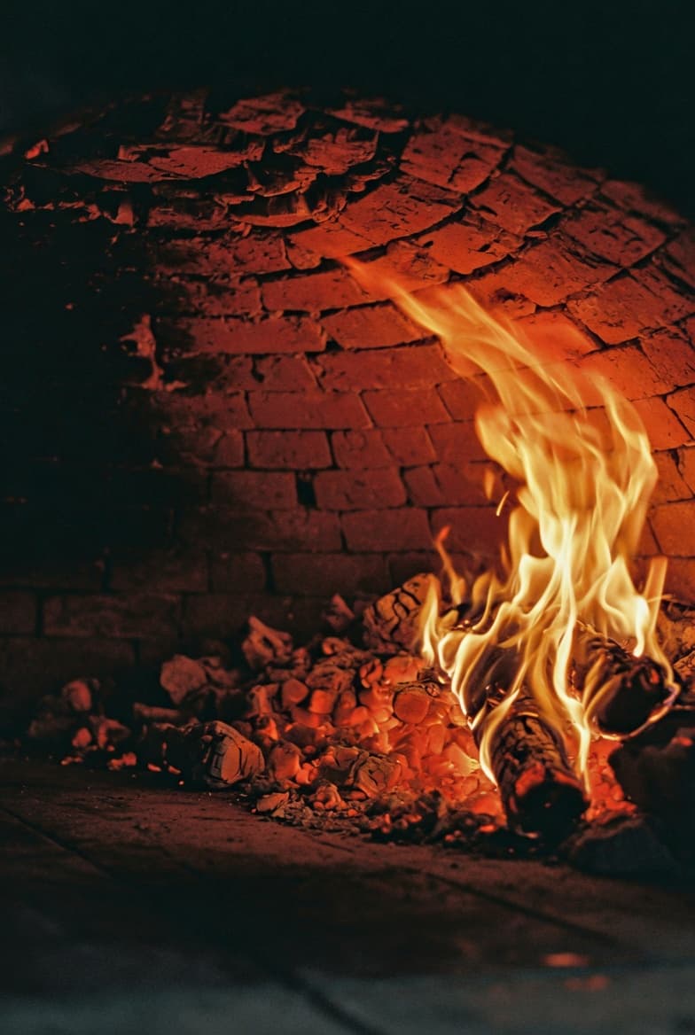 Vlammen in de houtoven, oranje gloed op het steen.
